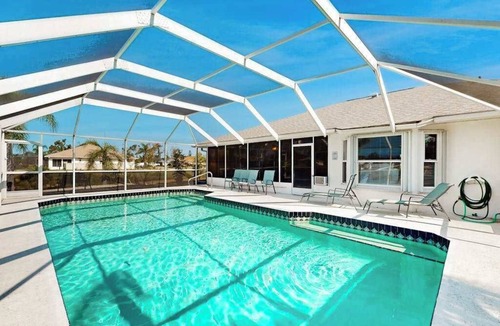 Pebble Beach House | Palm-lined waterfront retreat with enclosed pool, inviting patio, & central AC